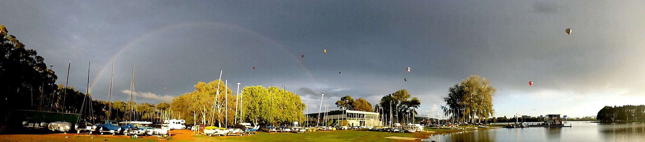 Heißluftballons fliegen in einen Regenbogen
